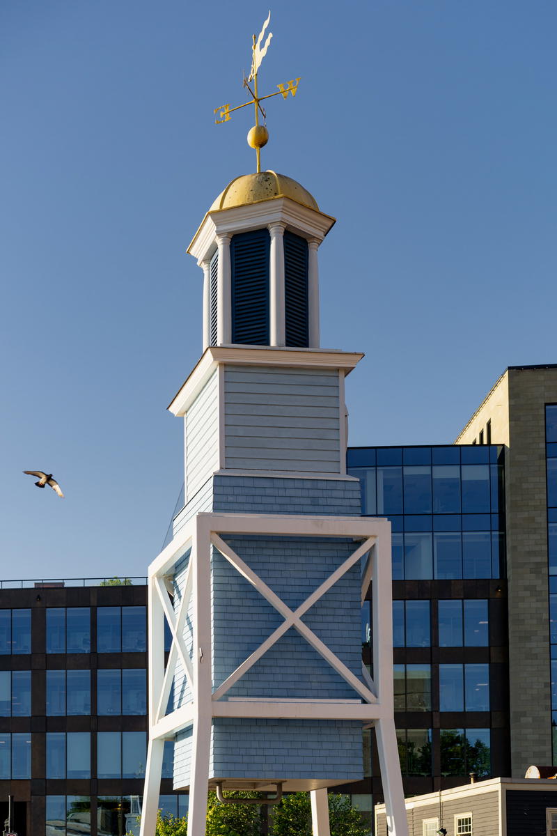 A clock tower with a weather vane on top of it