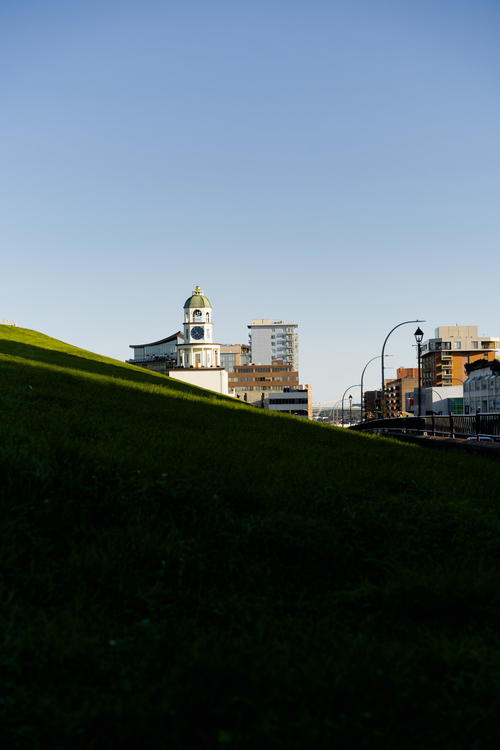 A grassy hill with a clock tower in the background