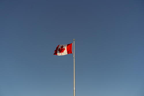 A canadian flag flying high in the sky