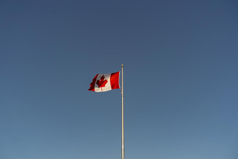 A canadian flag flying high in the sky