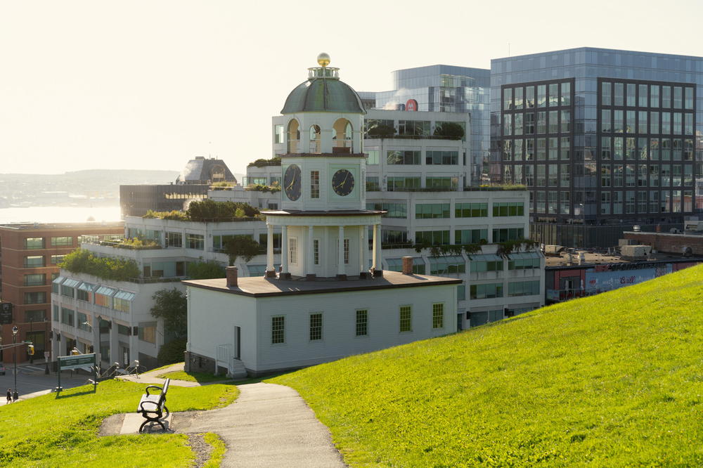A white building with a green roof on a hill