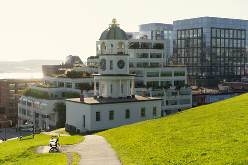 A white building with a green roof on a hill