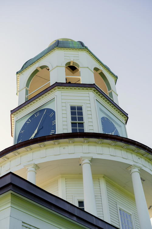 A large white clock tower with a sky background