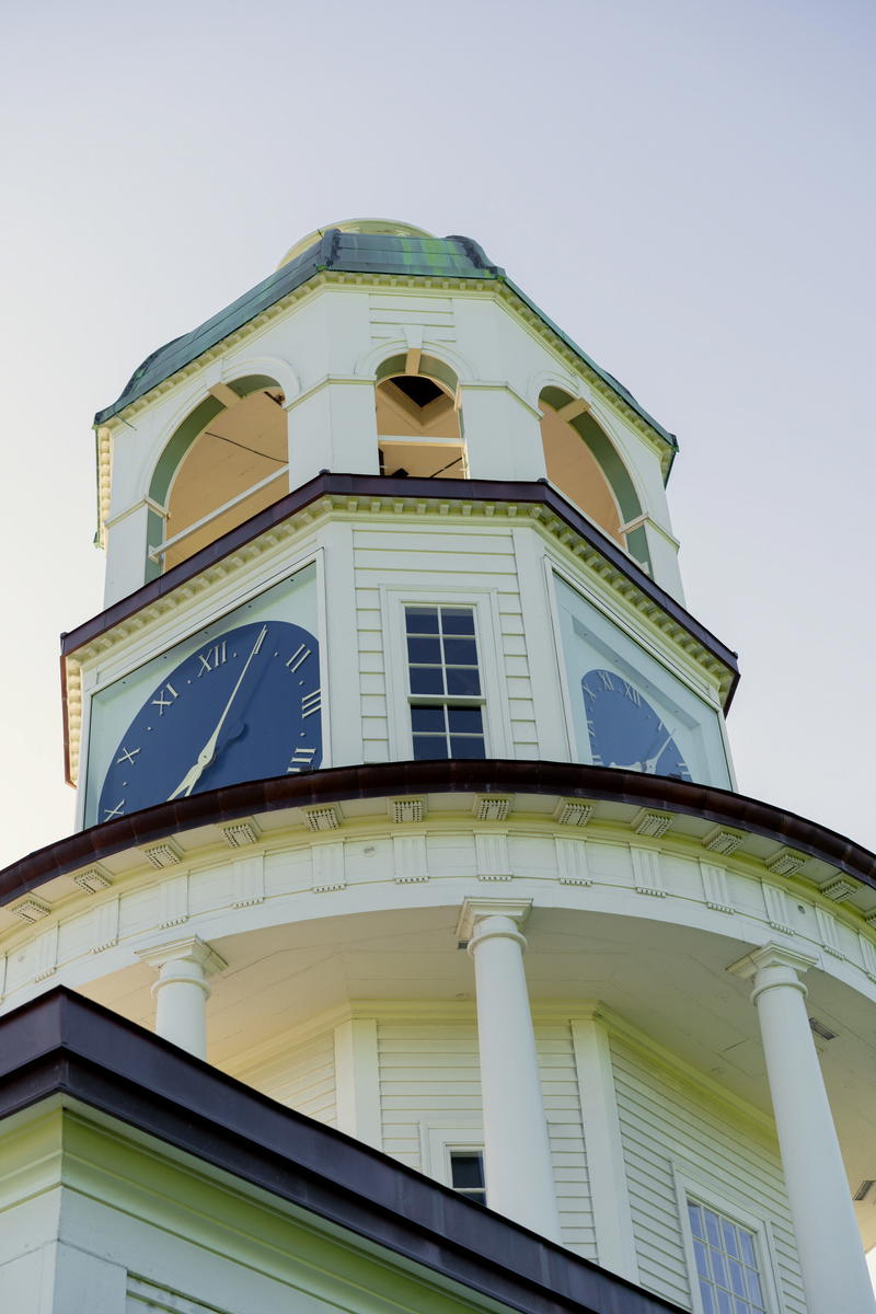 A large white clock tower with a sky background
