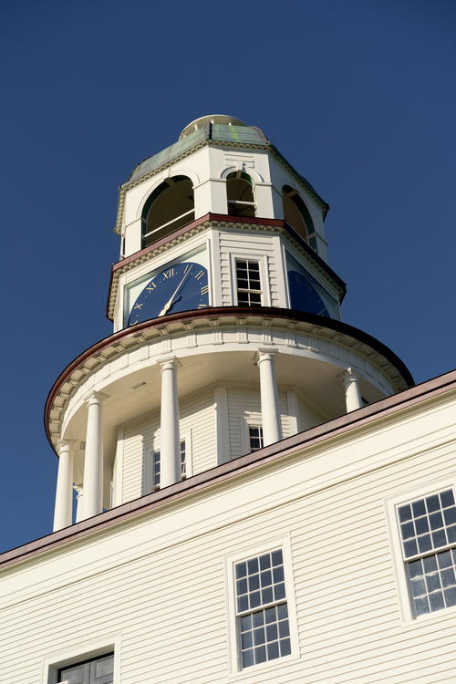 A white building with a clock on the top of it