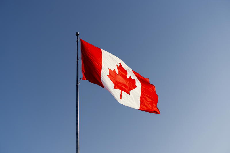 A canadian flag flying high in the sky