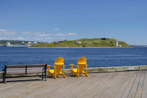 A couple of yellow chairs sitting on top of a wooden pier