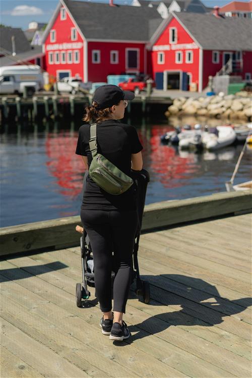 A women with a stroller on a pier with red buildings in the background in Lunenburg, Canada.