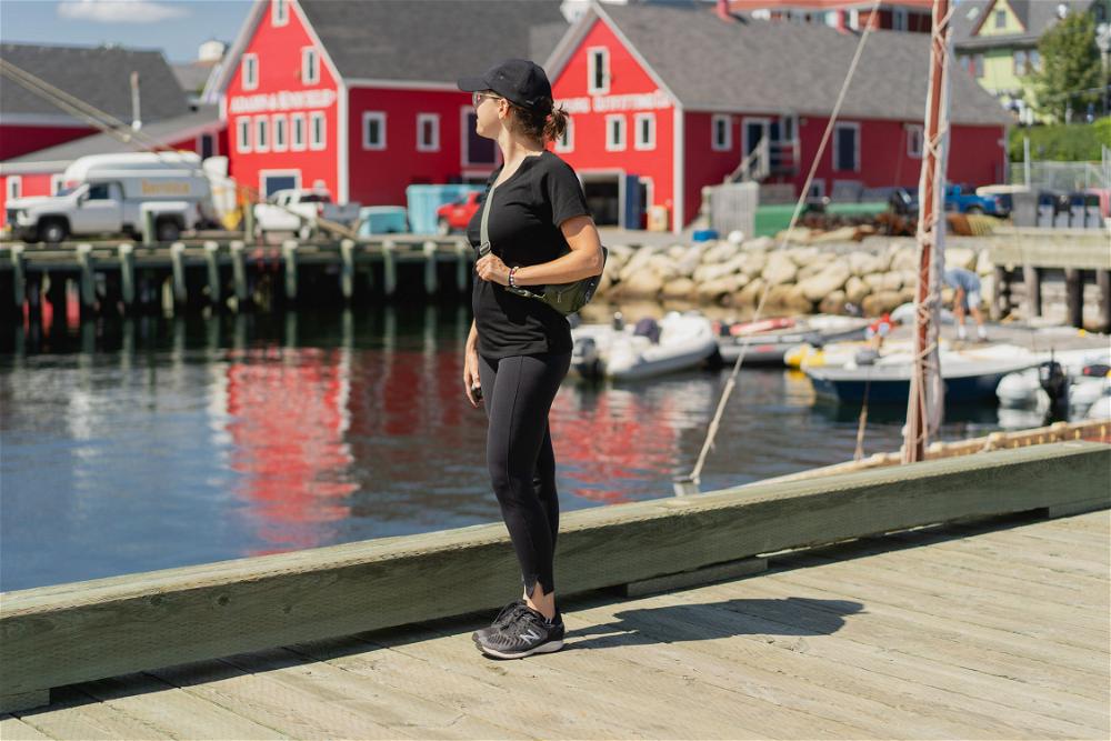 A women with a Kibou fanny back standing in front of red buildings in Lunenburg, Canada.