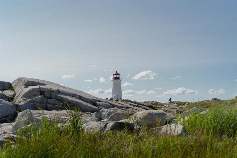 A view of Peggy's Cove Lighthouse with rocks in the foreground.