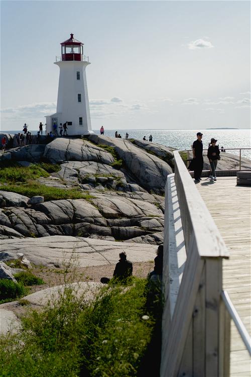 A view of Peggy's Cove with a viewing deck and rocks in the foreground.