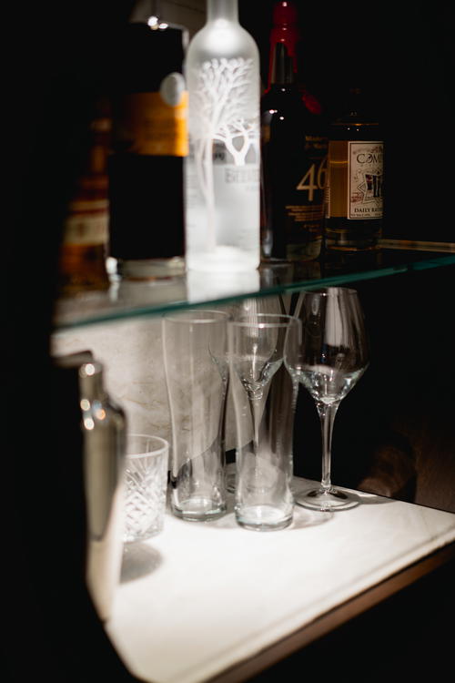 A glass shelf with liquor bottles and glasses on it inside Muir Hotel in Canada's Halifax.