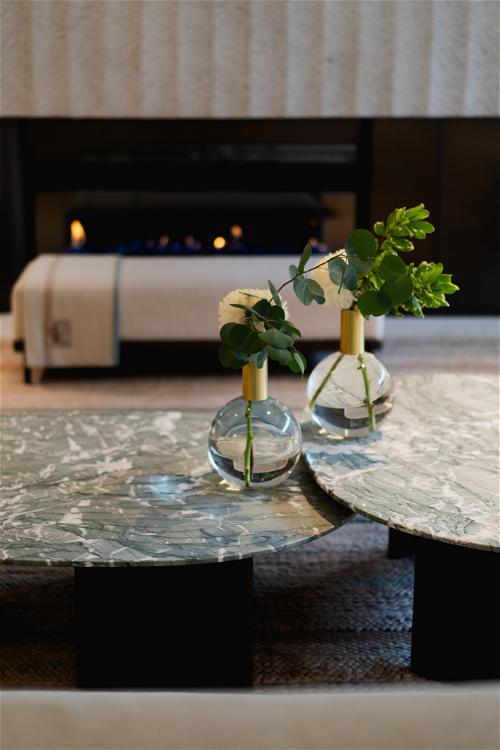 A marble coffee table in a living room with flowers in vases located in Halifax, Canada.