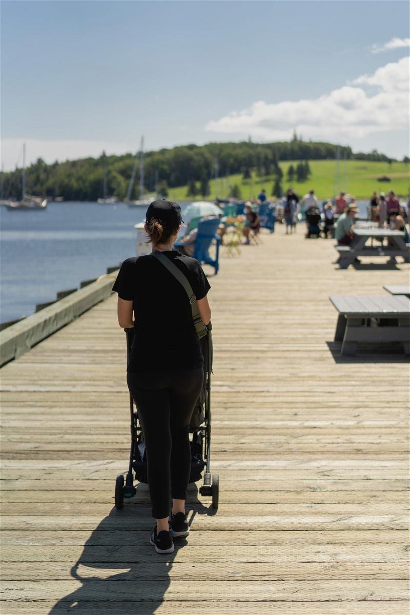 A woman strolling down a pier in Halifax, Canada with a stroller.