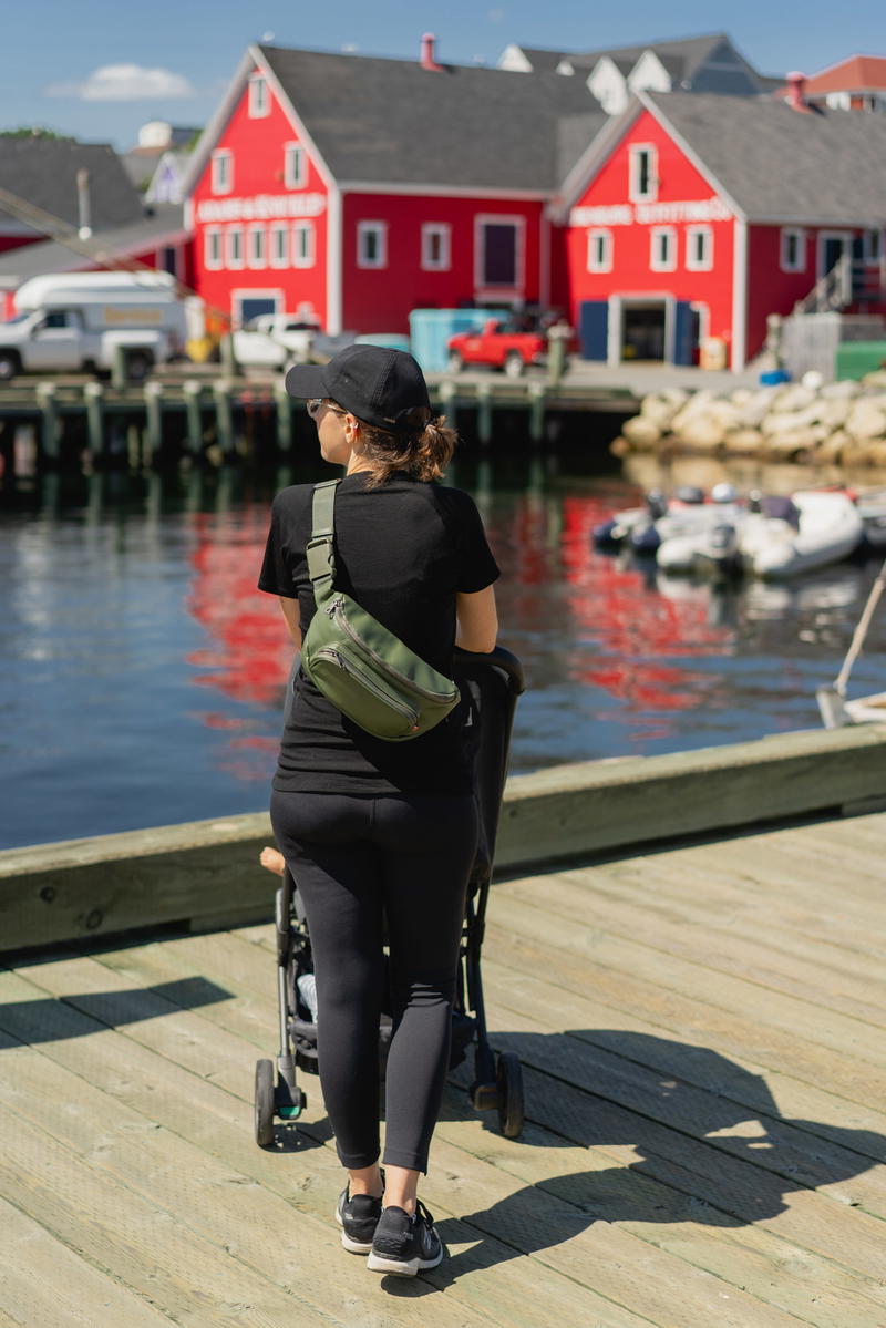 A woman strolling down a Halifax dock with a baby.