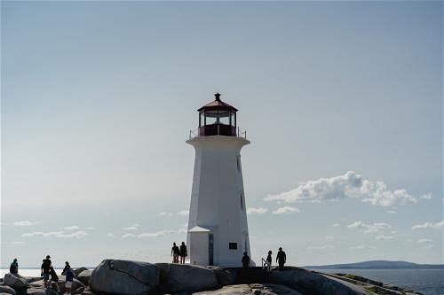 A lighthouse located in Halifax, Canada, with people standing on top of it.