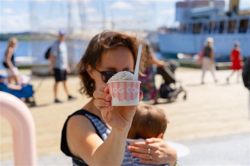 A woman holding up a cup of ice cream on a dock in Halifax, Canada.