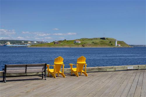 Two yellow chairs on a pier overlooking a body of water in Halifax, Canada.