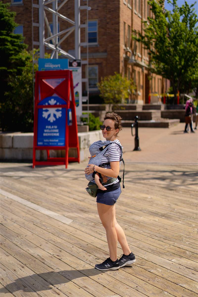 A woman holding a baby on a wooden boardwalk in Halifax, Canada.
