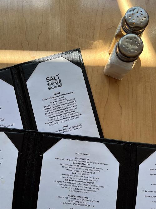 Two menus on a table in Halifax featuring salt and pepper shakers.