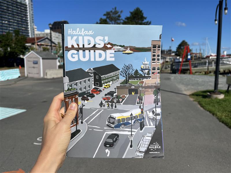 A person is holding up a children's guide to Halifax, Canada.