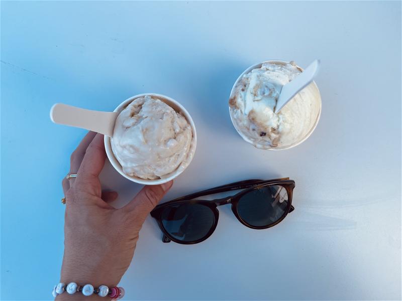 A person in Halifax, Canada, holding a cup of ice cream and sunglasses.