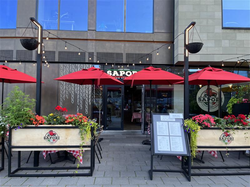 A restaurant in Halifax with red umbrellas and tables outside.