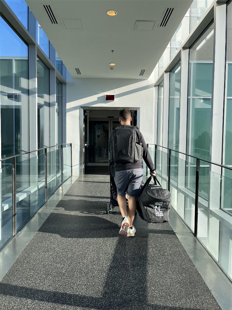 A man from Canada walking down a Halifax hallway with luggage.