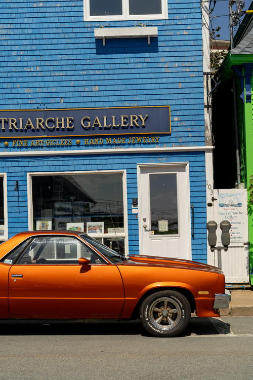 An orange car parked in front of a blue building