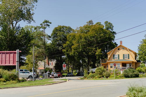 A yellow house with green shutters on a street corner