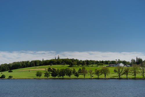 A large body of water surrounded by a lush green hillside