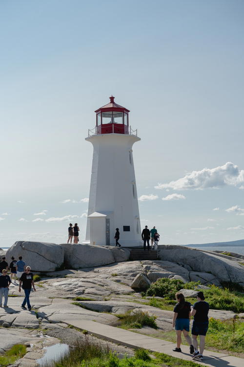 A group of people standing around a white and red lighthouse
