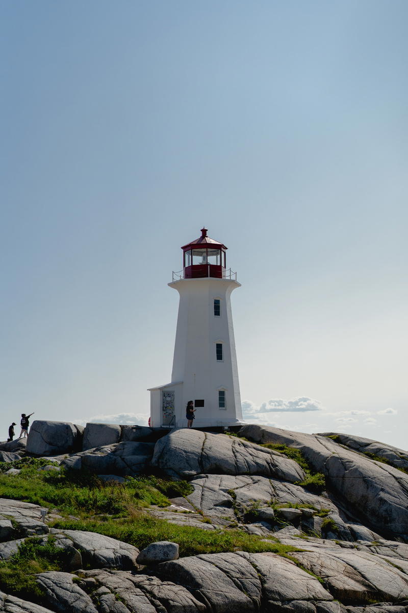 A white and red lighthouse sitting on top of a rocky hill