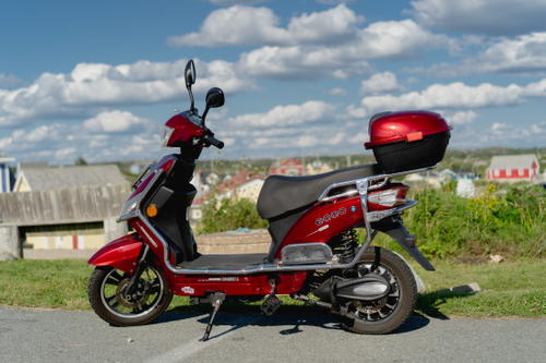 A red scooter parked on the side of the road