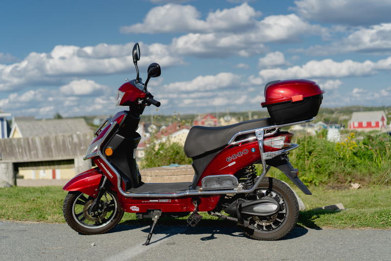 A red scooter parked on the side of the road