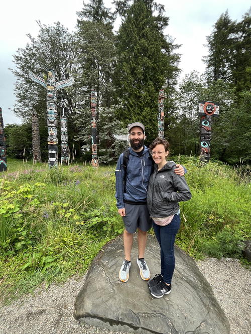 A man and a woman standing on a rock in front of a forest