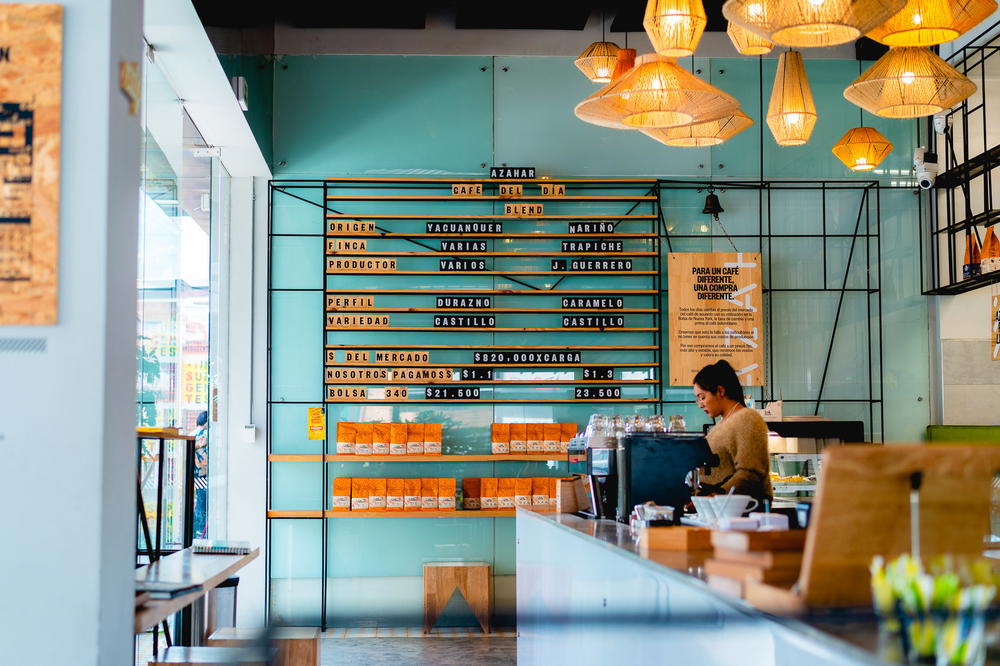 A woman is standing at the counter of a coffee shop.