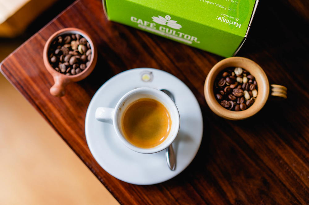 A cup of coffee and a box of coffee beans on a wooden table.