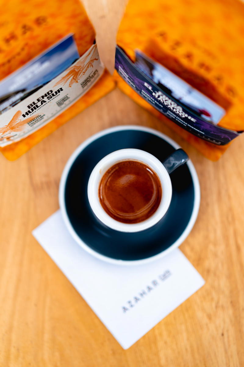 A cup of coffee on a table next to a bag of coffee.