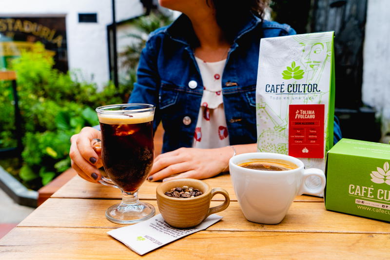 A woman is sitting at a table with a cup of coffee and a box of coffee.