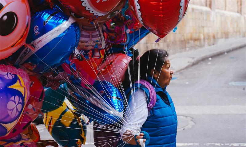 A girl carrying a bunch of balloons.