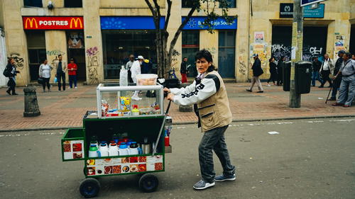 A man pushing a cart on the street.