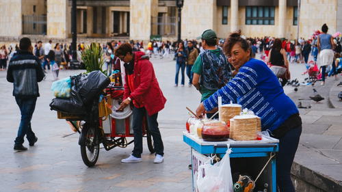 A woman selling food on a cart in a city.