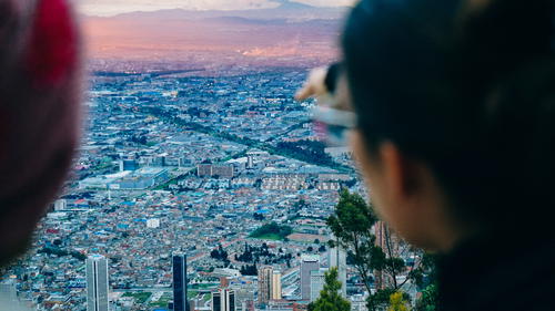 Two people looking at the city from the top of a mountain.