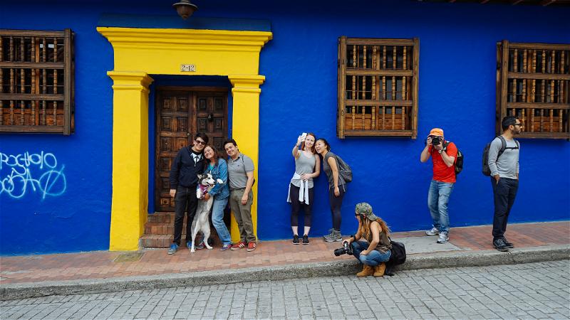 A group of people standing in front of a blue and yellow building.