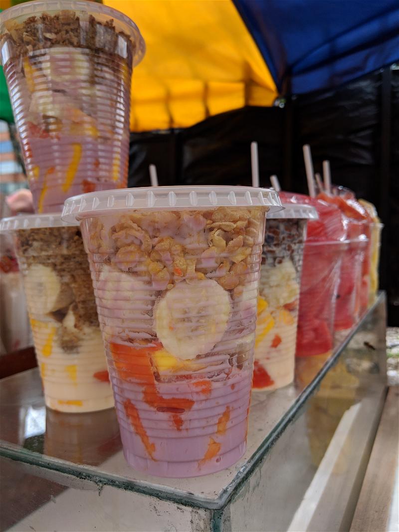 A display of plastic cups with fruit in them.
