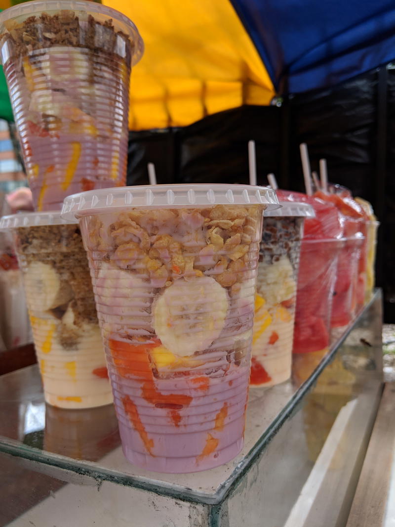 A display of plastic cups with fruit in them.