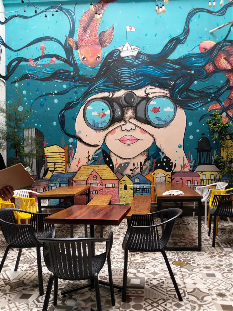 A table with chairs and a mural on the wall.
