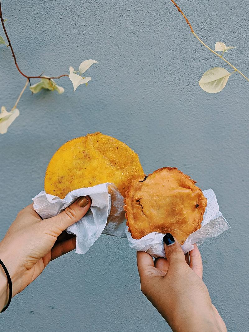 Two hands holding two small pastries.