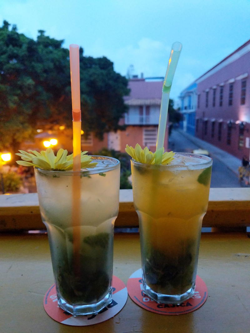 Two drinks with straws on a table.